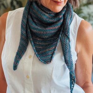 December Scarf knitting pattern in blue and purple striped yarn, worn bandana-style around the neck